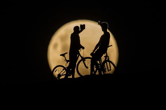 Bicyclists take photos of the supermoon in Lancelin, Australia.