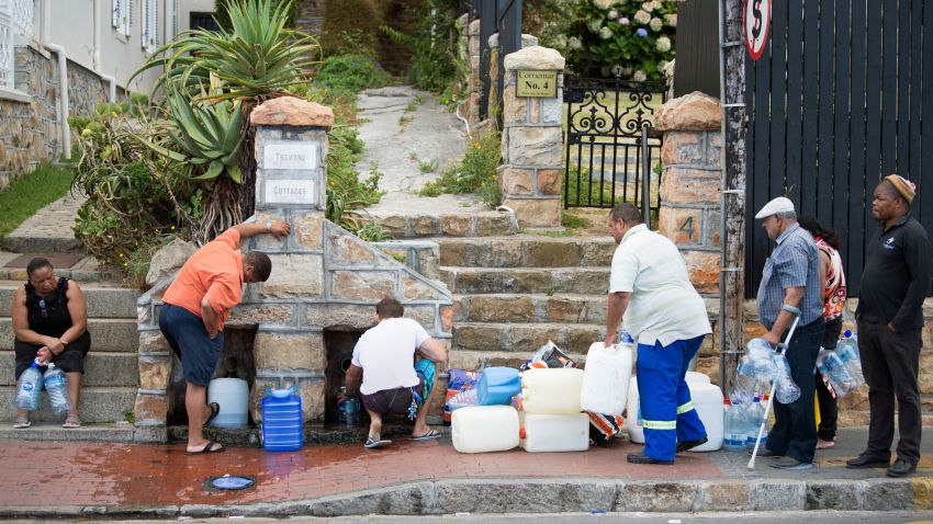 People collect drinking water from pipes fed by an underground spring, in St. James, about 25km from the city centre, on January 19, 2018, in Cape Town. 
Cape Town will next month slash its individual daily water consumption limit by 40 percent to 50 litres, the mayor said on January 18, as the city battles its worst drought in a century. / AFP PHOTO / RODGER BOSCH        (Photo credit should read RODGER BOSCH/AFP/Getty Images)