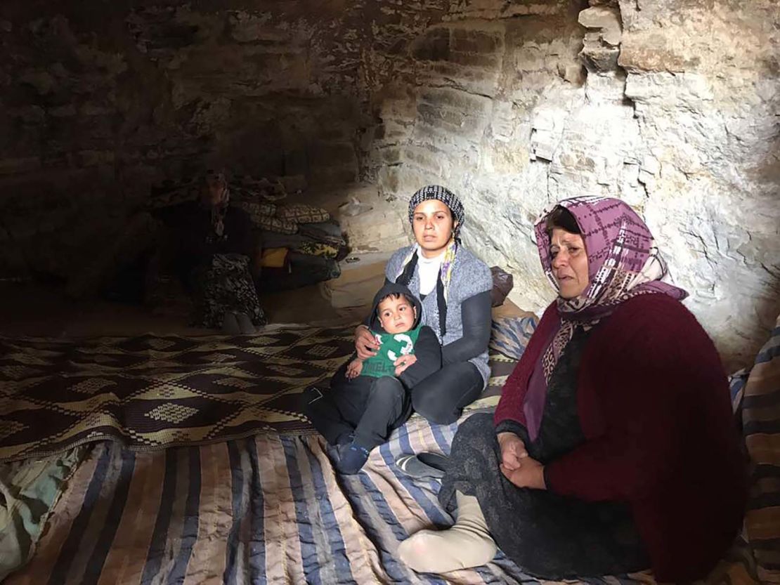 Afrin residents sit on blankets carpeting the floor of a cave.