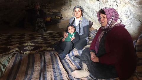 Afrin residents sit on blankets carpeting the floor of a cave.