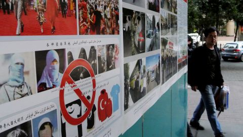 Pedestrians walk past anti-terror propaganda posters pasted along the streets of Urumqi, farwest China's Xinjiang region on September 16, 2014.