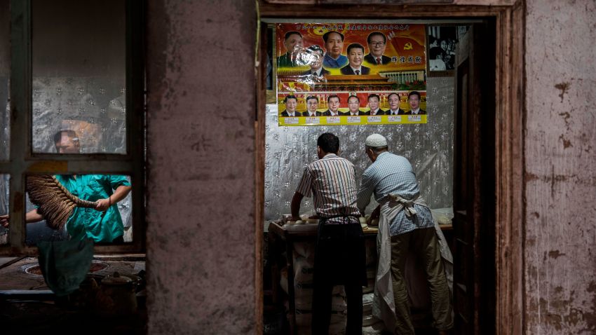 KASHGAR, CHINA - JULY 1: Under a poster showing Chinese leaders including the late Mao Zedong and the present President Xi Jinping, ethnic Uyghur men make bread at a local bakery on July 1, 2017 in the old town of Kashgar, in the far western Xinjiang province, China. Kashgar has long been considered the cultural heart of Xinjiang for the province's nearly 10 million Muslim Uyghurs. At an historic crossroads linking China  to Asia, the Middle East, and Europe, the city has  changed under Chinese rule with government development, unofficial Han Chinese settlement to the western province, and restrictions imposed by the Communist Party. Beijing says it regards Kashgar's development as an improvement to the local economy, but many Uyghurs consider it a threat that is eroding their language, traditions, and cultural identity.  The friction has fuelled a separatist movement that has sometimes turned violent, triggering a crackdown on what China's government considers 'terrorist acts' by religious extremists.  Tension has increased with stepped up security in the city and the enforcement of measures including restrictions at mosques. (Photo by Kevin Frayer/Getty Images)