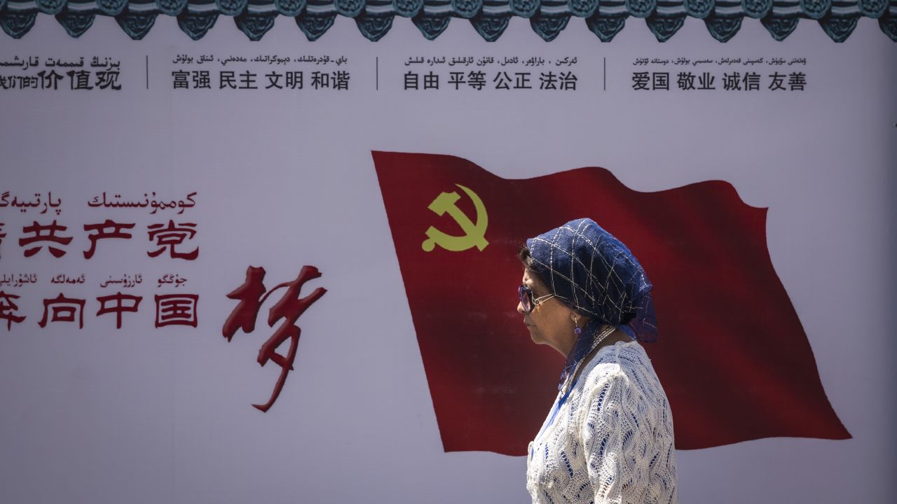 A Uyghur woman passes the Communist Party of China flag on a wall in Urumqi, the provincial capital of Xinjiang, in western China, June 2017. 