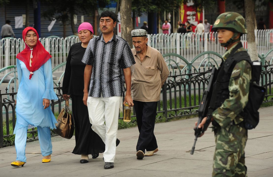 A Chinese paramilitary policeman watches as an ethnic Uyghur family walks in front of Urumqi's Grand Bazaar, July, 2009.