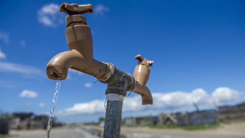 A communal tap runs as people collect water in an informal settlement near Cape Town on January 23.