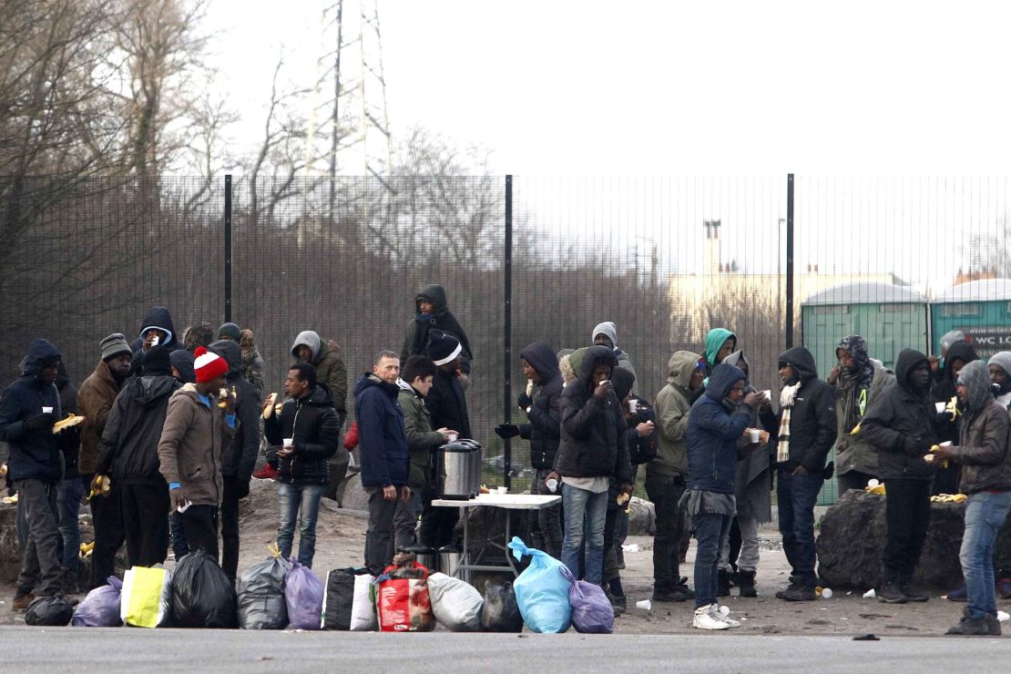 Migrants take a coffee and food provided by activists in Calais, northern France.