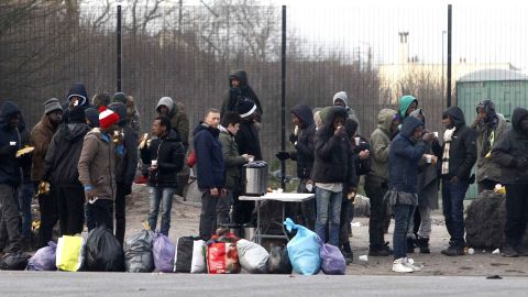 Migrants take a coffee and food provided by activists in Calais, northern France.