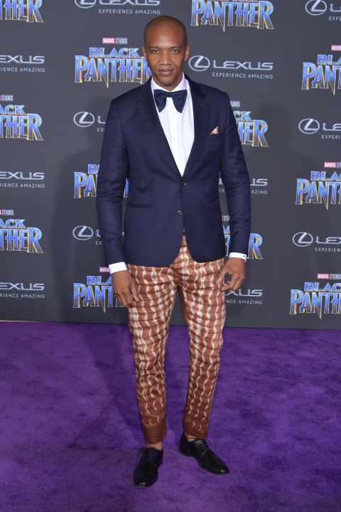 Actor J. August Richards attends the premiere in dark blue blazer and ankara-patterned trousers.