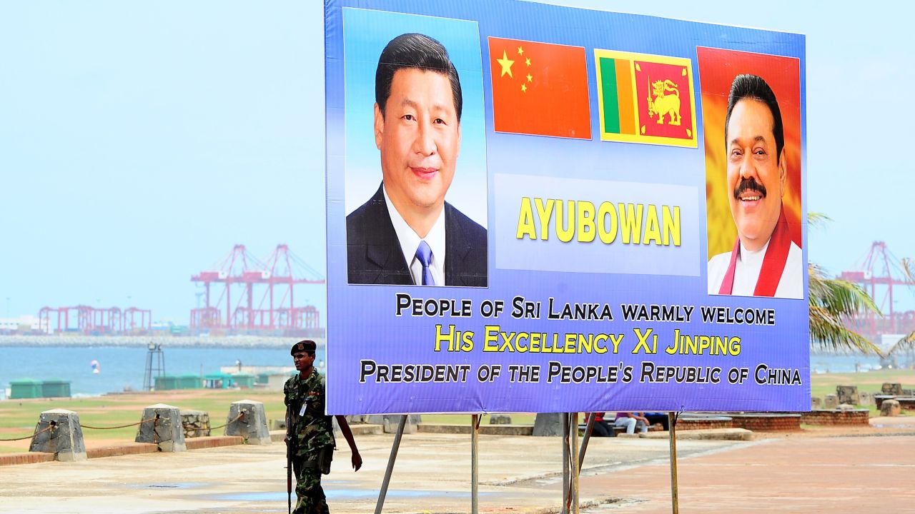 A Sri Lankan soldier walks past a billboard bearing portraits of Chinese President Xi Jinping and Sri Lankan President Mahinda Rajapakse, ahead's of Xi's visit to the Sri Lankan capital Colombo, September 15, 2014. 