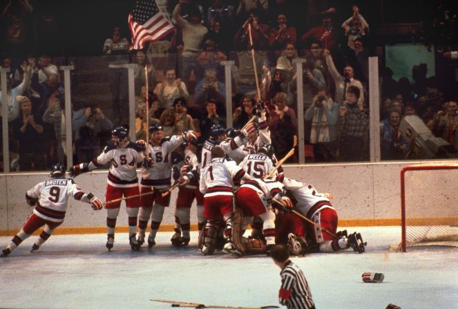 The US hockey team pounces on goalie Jim Craig after a 4-3 victory against the Soviets in the 1980 Olympics, as a flag waves from the partisan Lake Placid, N.Y. crowd, February 22, 1980.