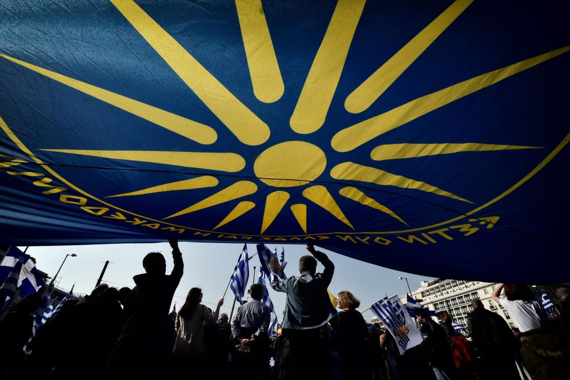 People are seen under a huge flag bearing a giant Vergina Sun (C), adopted by Greek Macedonians as a symbol of Greek Macedonia.