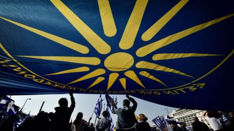 People are seen under a huge flag bearing a giant Vergina Sun (C), adopted by Greek Macedonians as a symbol of Greek Macedonia.