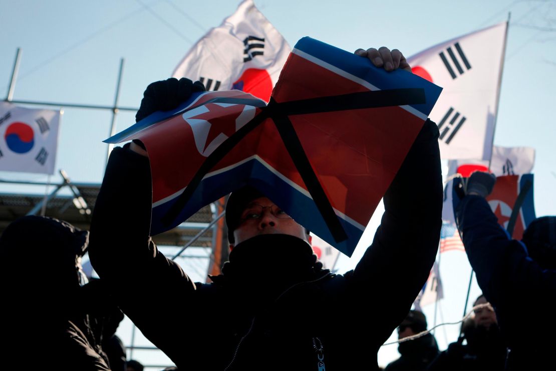 A protester rips up the North Korean flag outside Sunday's hockey match. 
