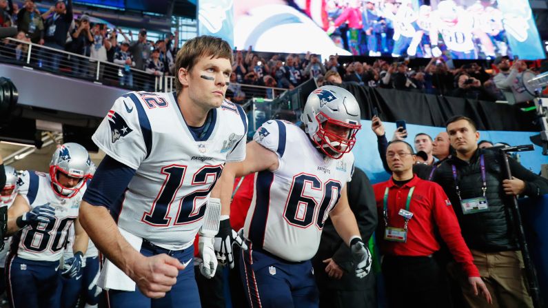 Brady and David Andrews (No. 60) lead the Patriots onto the field.