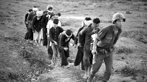A string of ten blindfolded Viet Cong suspects is led to his base camp by a soldier of the Korean Tiger division on Feb. 20, 1966.