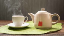 hot tea with steam and teapot on a table background. hot tea and teapot on leaf shape mat; Shutterstock ID 762799903