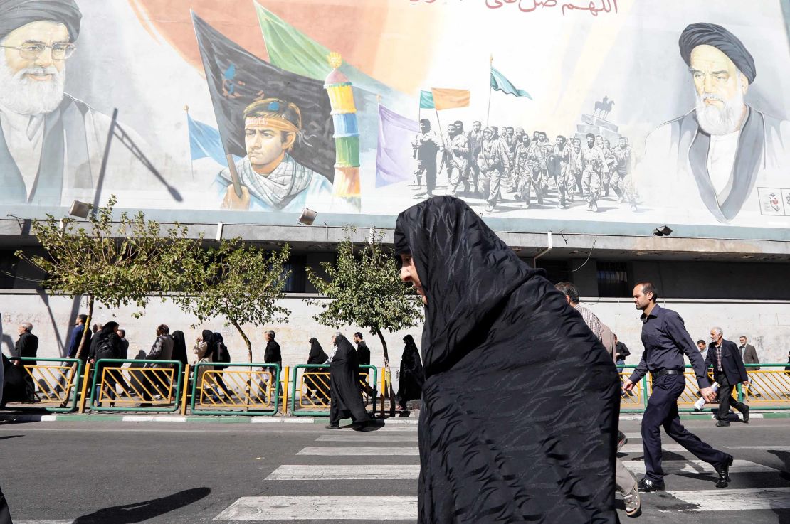 An Iranian woman walks past pictures of Iranian supreme leader Ayatollah Ali Khamenei (top L) and of late Iranian supreme leader Ayatollah Ruhollah Khomeini (top R), on October 13, 2017.

