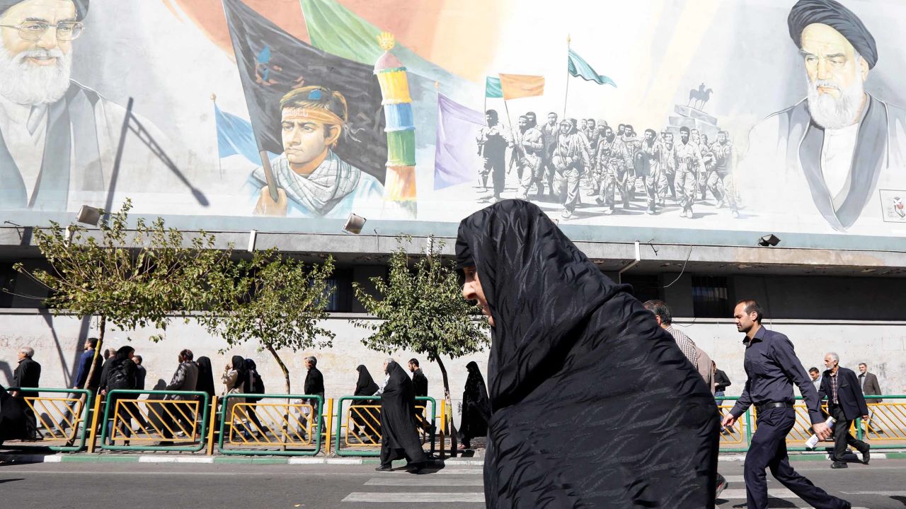 An Iranian woman walks past pictures of Iranian supreme leader Ayatollah Ali Khamenei (top L) and of late Iranian supreme leader Ayatollah Ruhollah Khomeini (top R), on October 13, 2017.