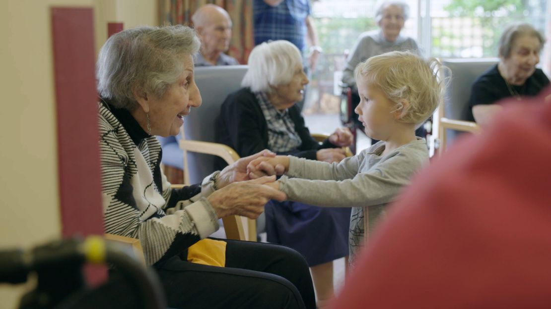 Fay Garcia, 90, visits with a child from her care home's on-site nursery.