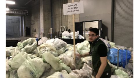 US Bank Stadium Sustainability Coordinator Bradley Vogel places a sign in the middle of a pile of trash bags for sorting on Monday. Green bags were for composting and white bags for waste.