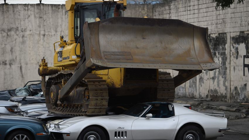 TOPSHOT - A bulldozer crushes luxury vehicles at a ceremony at the customs yard in Manila on February 6, 2018, after they were seized for being smuggled illegally.
President Duterte watched bulldozers flatten dozens of sports cars and other luxury vehicles February 6 as part of a drive to fight corruption at the country's customs bureau. / AFP PHOTO / TED ALJIBE        (Photo credit should read TED ALJIBE/AFP/Getty Images)