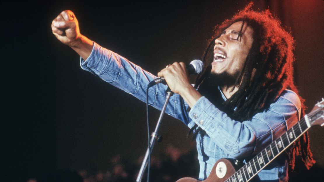Jamaican Reggae musician, songwriter, and singer Bob Marley performs on stage, in a concert at Grona Lund, Stockholm, Sweden. He extends his fist as he sings into the microphone, with an electric guitar. (Photo by Hulton Archive/Getty Images)