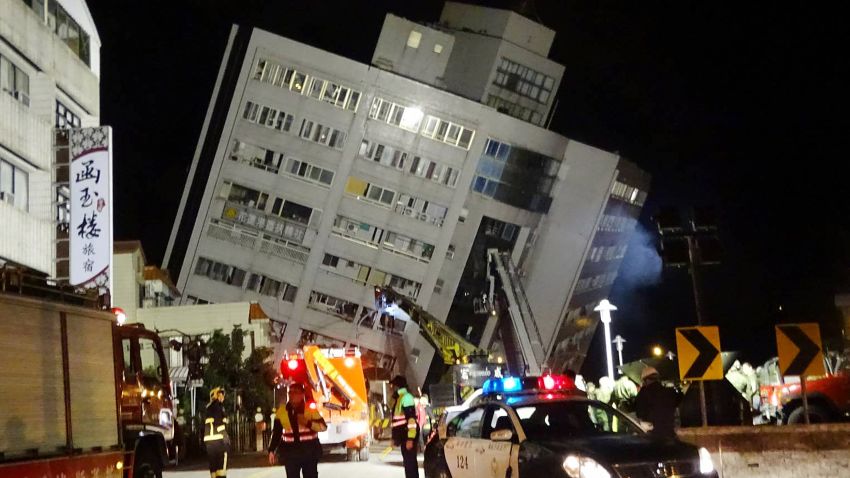 Rescuers are seen entering a building that collapsed onto its side from an early morning 6.4 magnitude earthquake in Hualien County, eastern Taiwan, Wednesday, Feb. 7 2018.  Rescue workers are searching for any survivors trapped inside the building. (AP Photo/Tian Jun-hsiung)