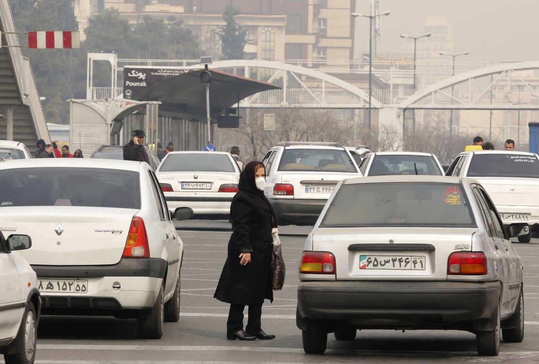 An Iranian woman wearing a face mask waits at a bus stop as heavy pollution hit new highs in Tehran on February 5, 2018.  (Photo credit:  ATTA KENARE/AFP/Getty Images)