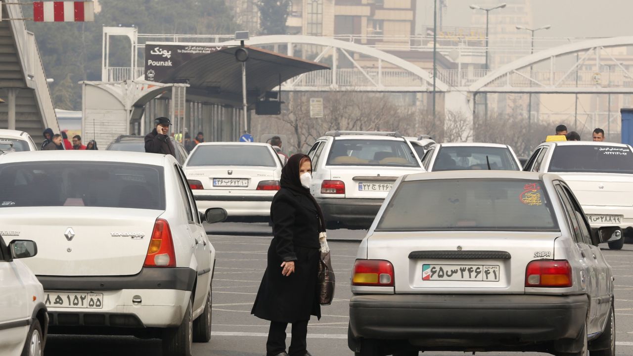 An Iranian woman wearing a face mask waits at a bus stop as heavy pollution hit new highs in Tehran on February 5, 2018. (Photo credit: ATTA KENARE/AFP/Getty Images)