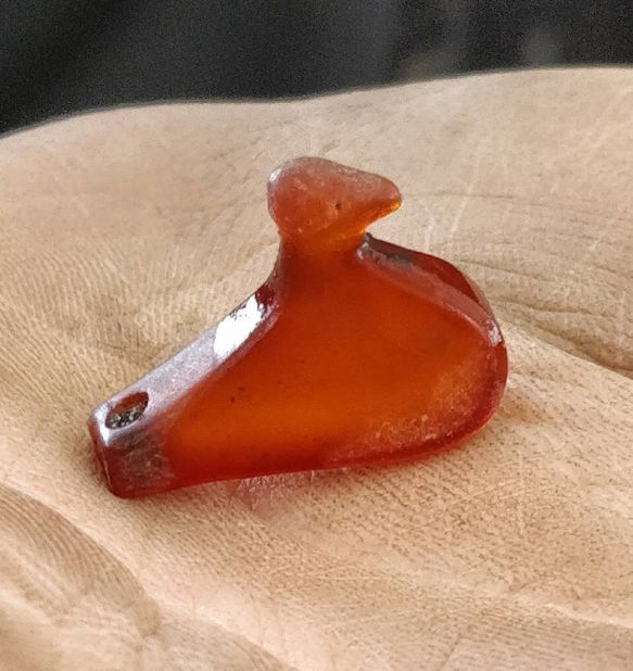This is a small bird figure carved in amber. The hole in the tail suggests it could have been used as a bead in a necklace.
