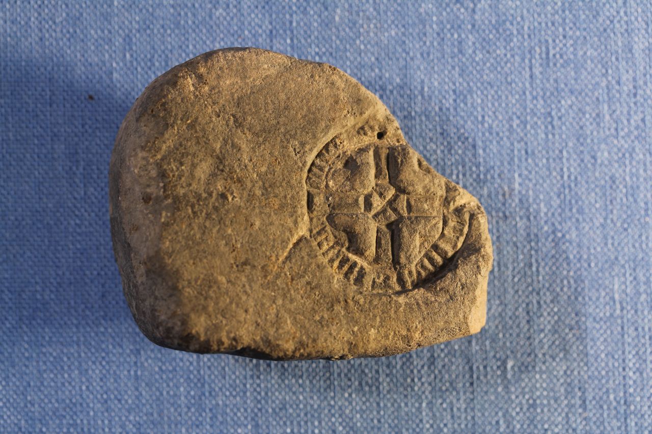 This stone would have been a casting mold for small lead amulets. The cross symbol may show influence from Christian mission.