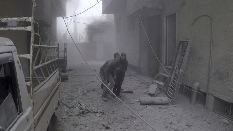 In a White Helmets photo, two civilians flee after airstrikes Monday in a rebel-held Damascus suburb.