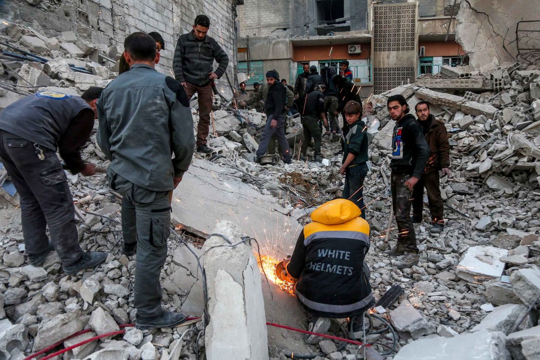 White Helmet volunteers and other civilians clear rubble from a collapsed building airstrikes in Arbin, Eastern Ghouta, on Tuesday.