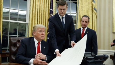 White House staff secretary, Rob Porter, center, works with President Donald Trump as Reince Priebus watches.