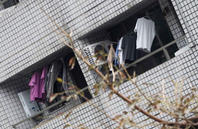 Clothes hang on the balcony of a leaning apartment building.