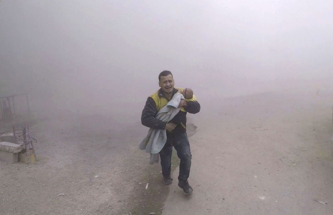 In a White Helmets photo, a paramedic flees with his wounded son after airstrikes near Damascus.