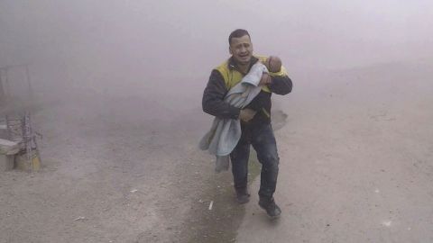 In a White Helmets photo, a paramedic flees with his wounded son after airstrikes near Damascus.
