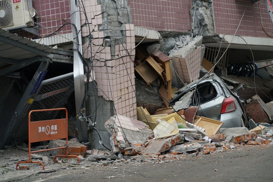 A car is crushed by a building that shifted off its foundation.