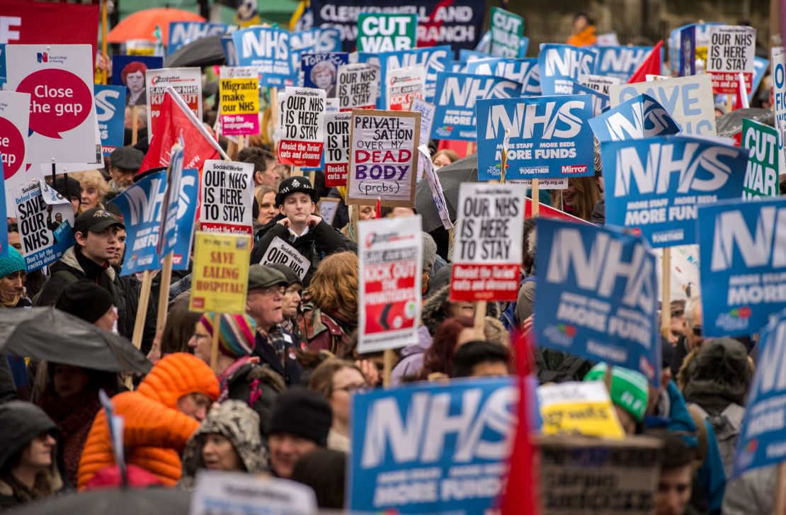 Demonstrators carry placards during a protest against the government's health policy on February 3 in London.