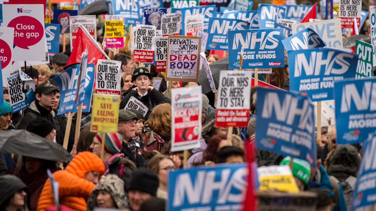 Demonstrators carry placards during a protest against the government's health policy on February 3 in London.
