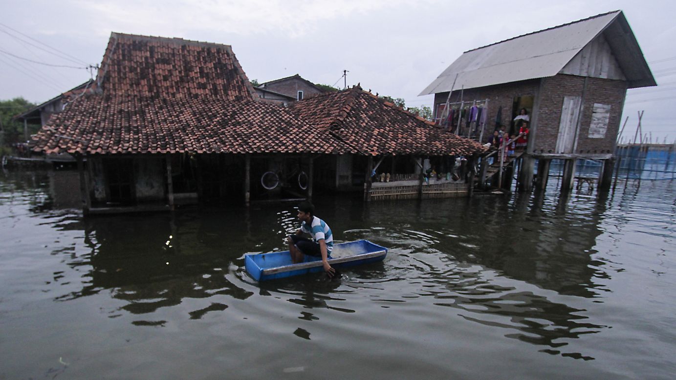 A man uses a handmade boat to reach his waterlogged home in Sriwulan village, Indonesia, on Friday, February 2. The local marine and fisheries office said the tidal flooding was caused by coastal abrasion due to the disappearing mangrove forests over the last 20 years.