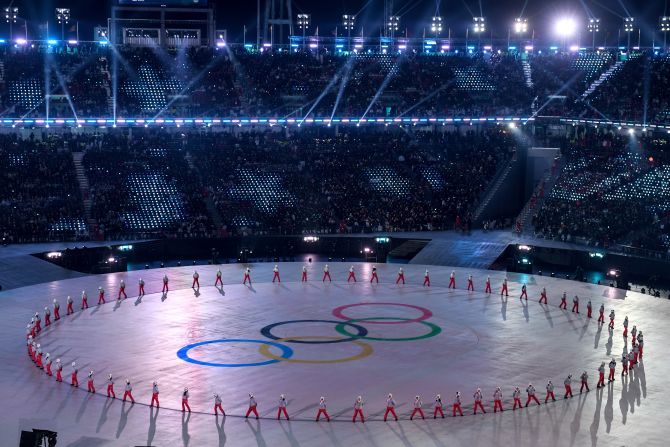 Participants perform around a design of the Olympic rings.