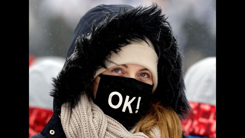 A fan keeps warm during a weather delay before the men's slopestyle qualification.