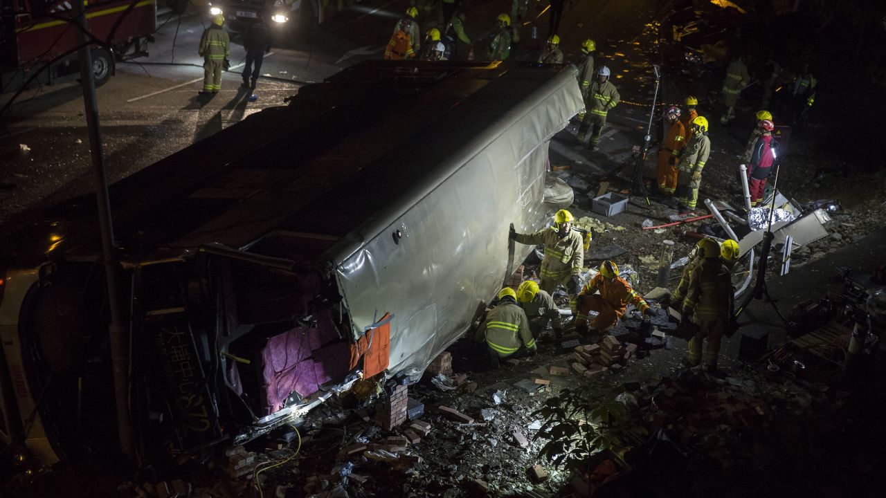 Firefighters dig through  debris after a deadly bus crash on Saturday in Hong Kong. 