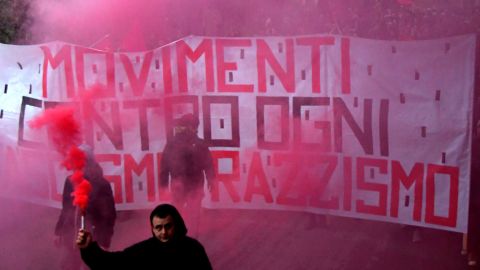A man holds a flare in front of an anti-fascism banner during a protest Saturday in Macerata.