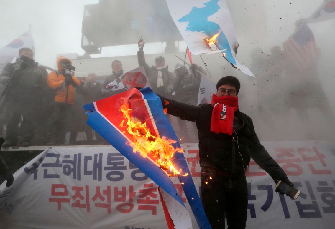 A protester burns a North Korean flag during a rally against North Korea's participation in the 2018 Pyeongchang Winter Olympics.