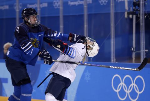 Monique Lamoureux-Morando of the United States, takes a punch from Rosa Lindstedt of Finland, during the preliminary round of the women's ice hockey.