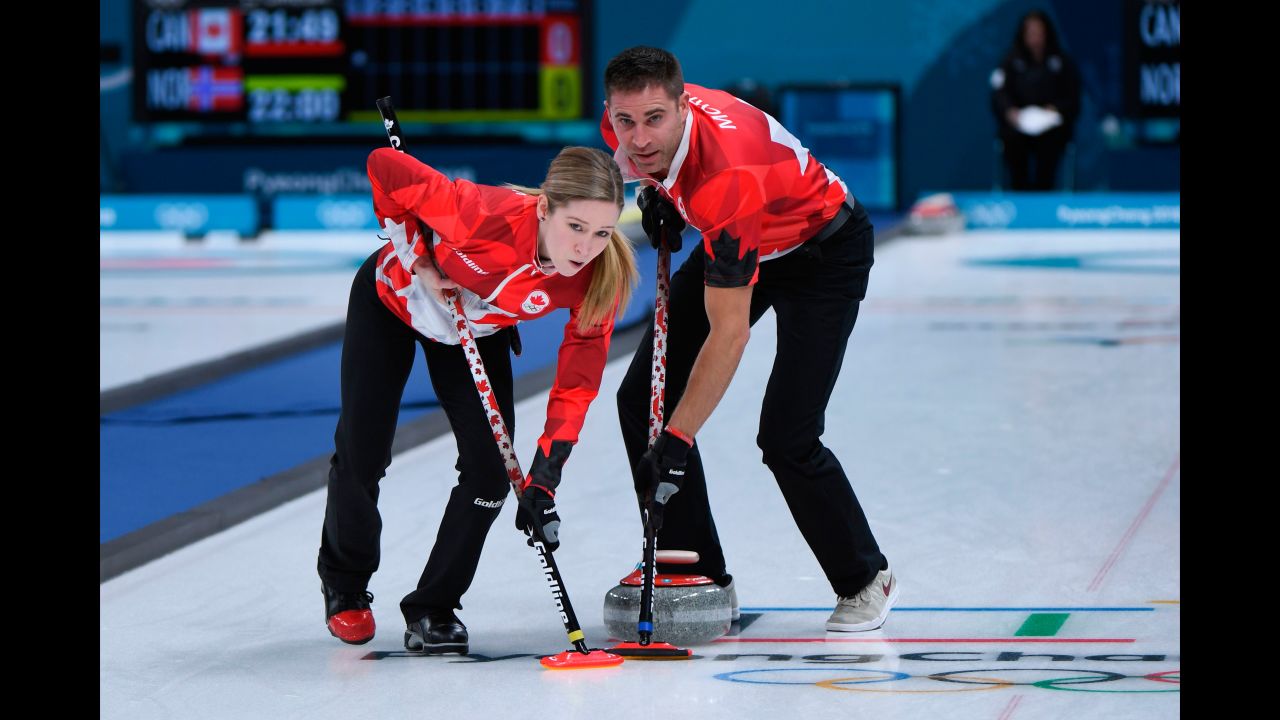 Canada's Kaitlyn Lawes and John Morris brush the ice during a curling match.