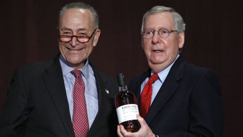US Senate Minority Leader Chuck Schumer, a New York Democrat, at left, presents Senate Majority Leader Mitch McConnell, a Kentucky Republican, at right, with a bottle of bourbon at the University of Louisville's McConnell Center. (Bill Pugliano/Getty Images)