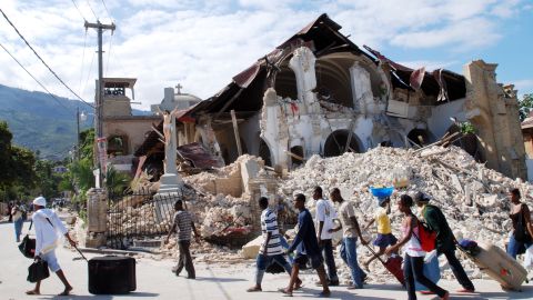 Haitians walk past the collapsed Sacre Coeur Church in Port-au-Prince on January 14, 2010, following the devastating earthquake that rocked Haiti two days before